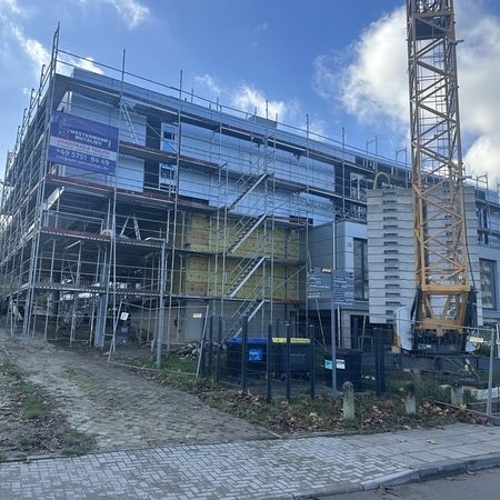 Komplett eingerüstetes Gebäude auf einem Baugrundstück mit Baukran im Hintergrund.